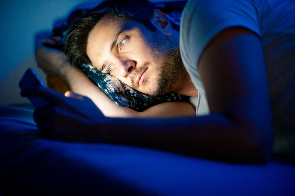 Ecran de telefon în întuneric, sursă de lumină albastră care întârzie secreția de melatonină